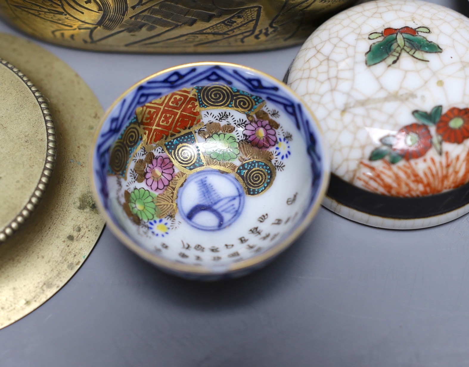 A collection of various Chinese porcelain lids/covers, a clobbered blue and white tea bowl, a brass hand warmer and a hardstone tablet